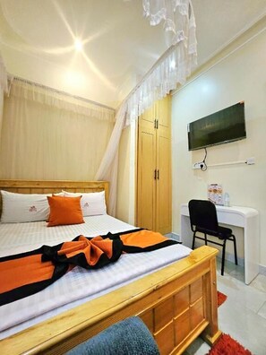 Un dormitorio con cama, escritorio, silla, televisor y armario.