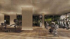 Un gimnasio espacioso con diversos equipos de ejercicio, incluyendo cintas de correr y máquinas de pesas, y un pilar grande en el centro.