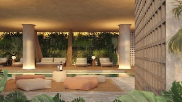 A modern lounge area with seating, a pool, and lush greenery.