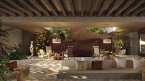Un área de estar interior con piso de piedra, mobiliario de madera y plantas en macetas.