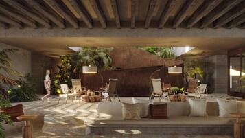 An indoor lounge area with a stone floor, wooden furniture, and potted plants.