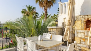 An outdoor patio with a table and chairs, a lamp, and a stone wall. - Sunpoint Hotel Bodrum (Bodrum)