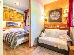 Ein gemütliches Zimmer mit einem Bett, einer Couch, Holzwänden, einem Fernseher und Wanddekoration.