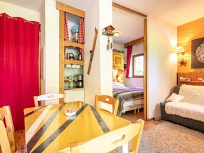 Ein gemütliches Zimmer mit Esstisch, Stühlen, einem Bett und einer kleinen Küchenzeile.