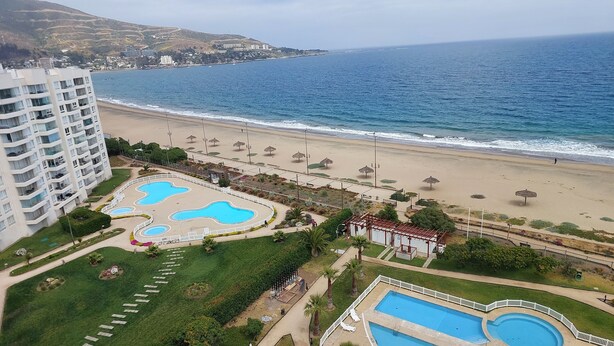A resort with multiple swimming pools, a beach, and a view of the ocean. - Cozy apartment with a beautiful ocean view (Valparaíso)