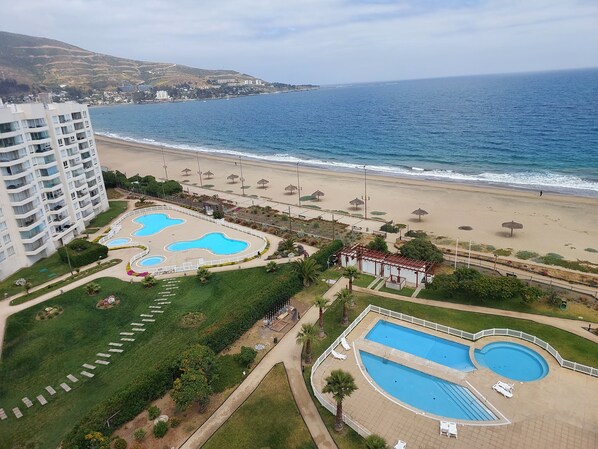Ein Resort mit mehreren Schwimmbecken, einem Strand und Blick auf den Ozean.