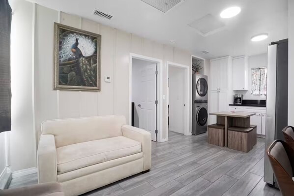 A modern living room with a sofa, a dining table, and a kitchen area with appliances.