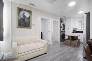 A modern living room with a sofa, a dining table, and a kitchen area with appliances. - Private Cozy Guest House w/ Parking Slps 4 (Santa Clarita)