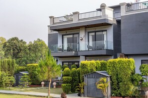Un edificio moderno de dos pisos con balcón, garaje y jardines bien cuidados.