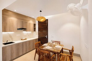A modern kitchen with wooden cabinets, a dining table set for four, and a ceiling fan.