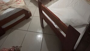 A room with four wooden beds, a mirror, a shelf, and a window with curtains.