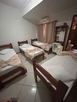 Una habitación con cuatro camas de madera, un espejo, un estante y una ventana con cortinas.
