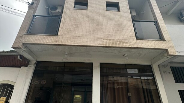 A multi-story building with a tiled facade, large windows, and a ground-level entrance with a glass door.