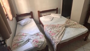 Two single beds with wooden frames, a tiled floor, and a window with curtains.