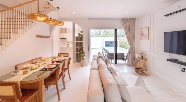 Un salon moderne avec un canapé, une table à manger et un téléviseur.