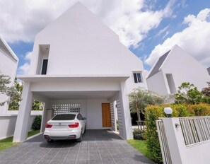 A modern white two-story house with a car parked in the driveway.