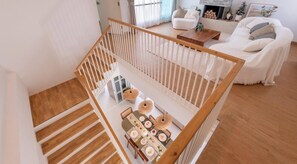 Un intérieur moderne avec un escalier en bois, un coin repas avec une table dressée pour quatre personnes et un salon avec un canapé et une cheminée.