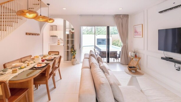A modern living room with a dining area, a staircase, and a TV. - Минималистичная вилла в Сарабури с видом на горы До 12 гостей (Tambon Song Khon)