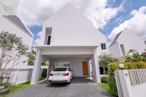Een modern wit huis met twee verdiepingen, met een auto op de oprit.