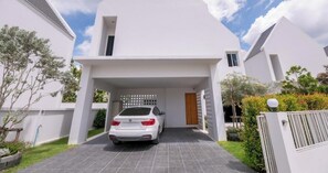 A modern white two-story house with a car parked in the driveway.