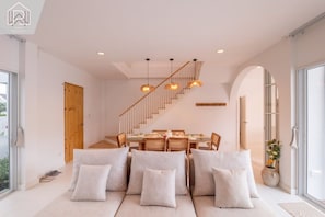 Een modern interieur met een eethoek, bank, trap en grote ramen.