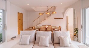 A modern interior with a dining area, sofa, staircase, and large windows. - Villa Kolam Minimalis Pemandangan Gunung di Saraburi 12 Pax (Tambon Song Khon)