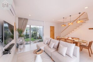 Una sala de estar moderna con un sofá, una mesa de comedor y una escalera.