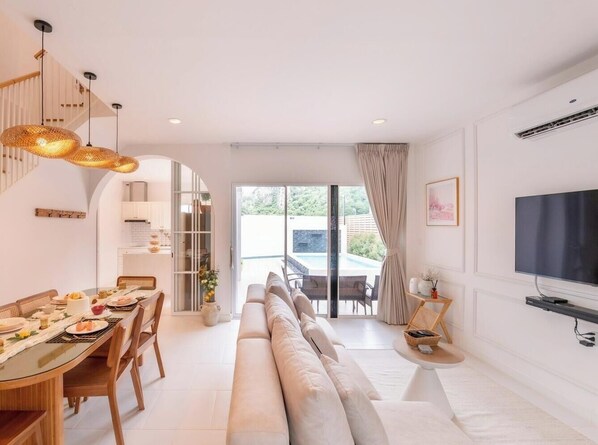 Ein modernes Wohnzimmer mit Sofa, Esstisch und Fernseher.