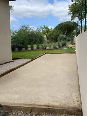 A concrete patio area with a grassy lawn and trees in the background.