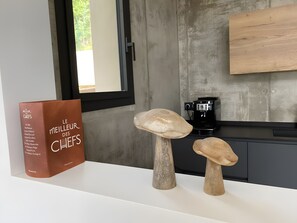 Una encimera de cocina con una cafetera, un libro titulado 'Le Meilleur des Chefs' y dos objetos con forma de hongo.