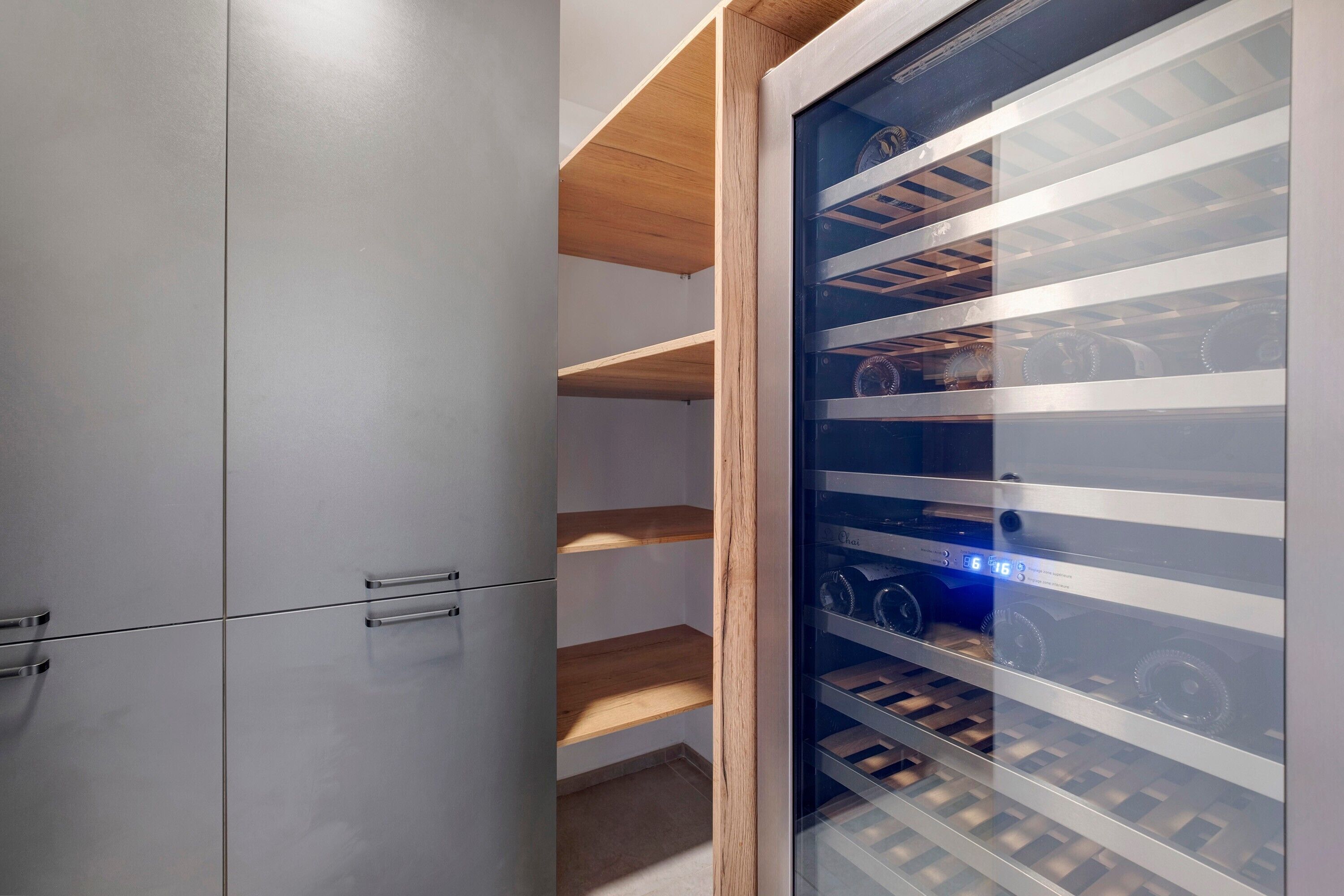 A modern storage unit with multiple compartments, including a glass-fronted section with shelves.