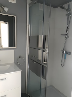 Ein modernes Badezimmer mit Duschkabine aus Glas, einem weißen Waschbecken und einem Spiegel.