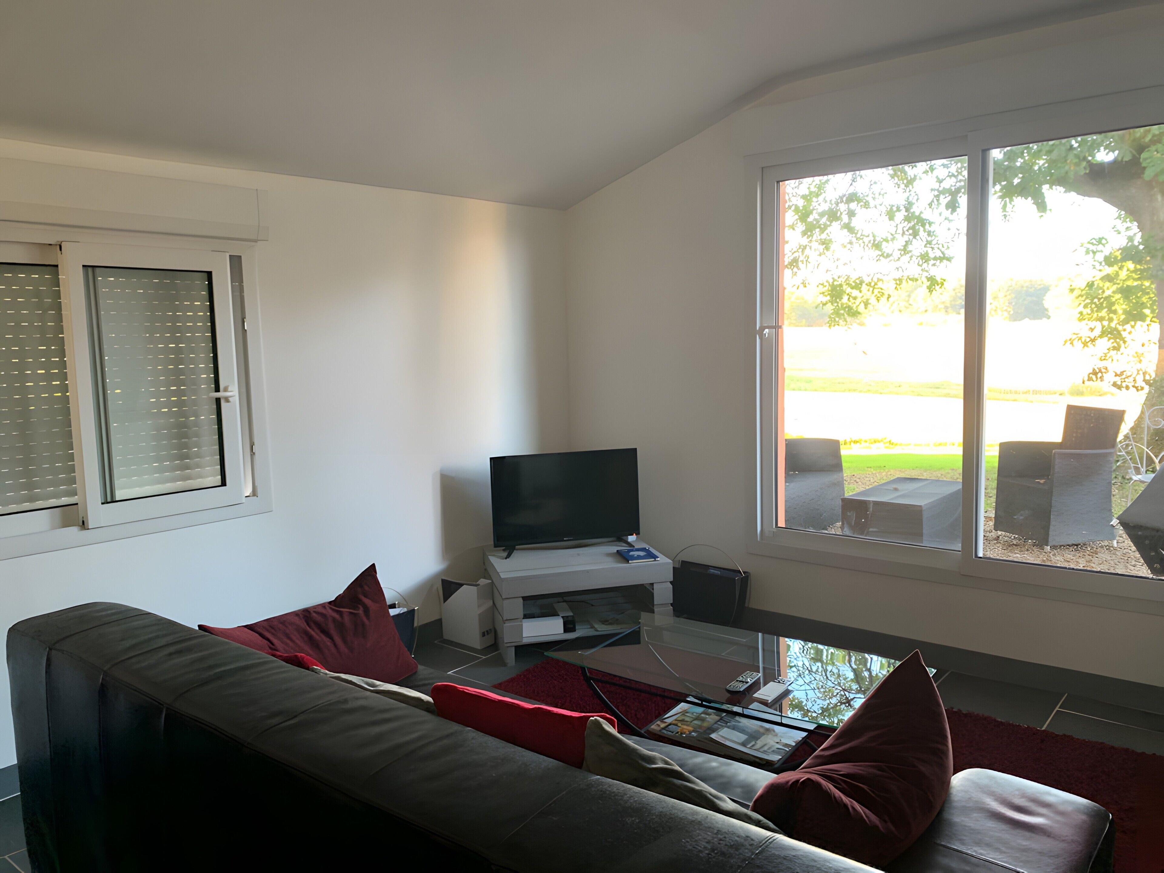A living room with a sofa, a flat-screen TV, a coffee table, and a window with a view of the outdoors.