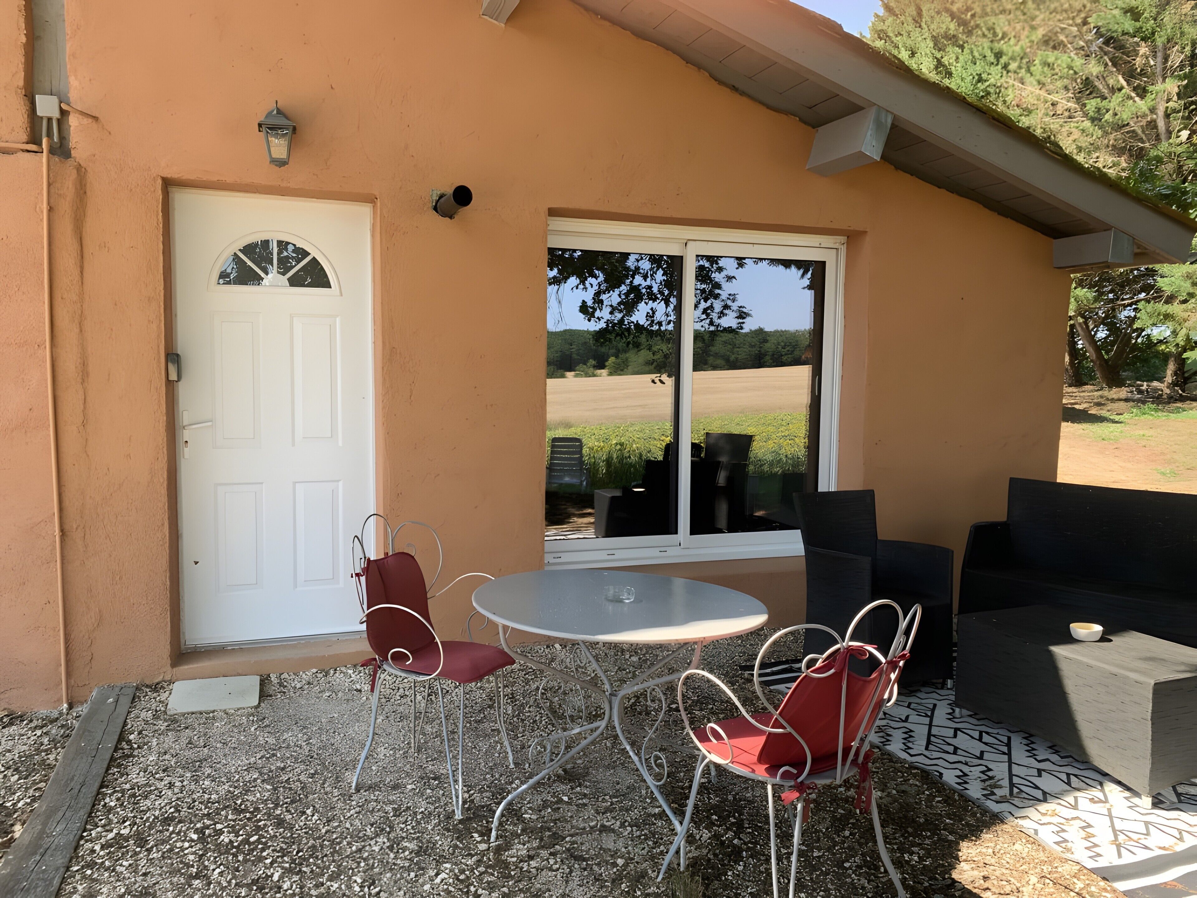 A patio with a table and chairs, a white door, and a view of a field.