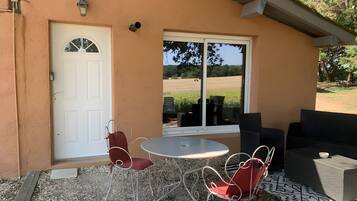 A patio with a table and chairs, a white door, and a view of a field.