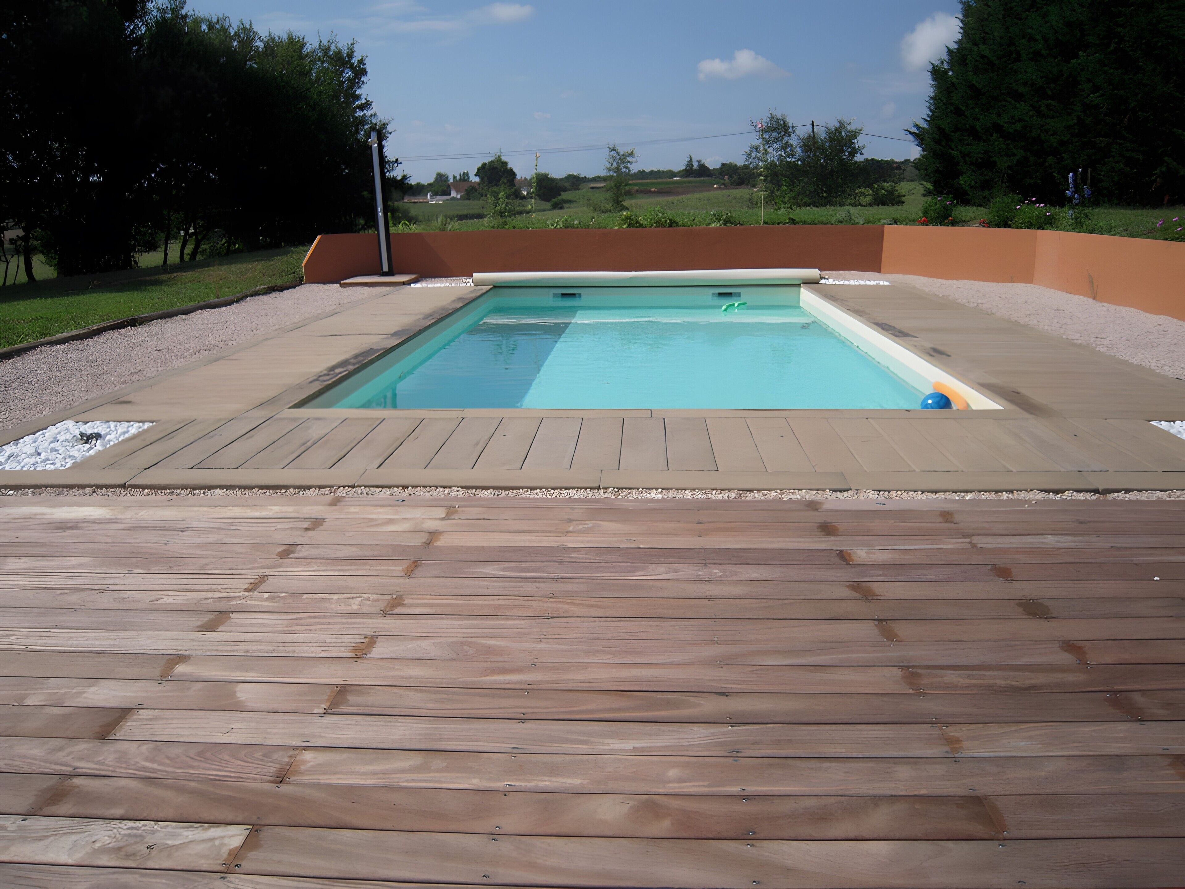 Ein rechteckiger Pool mit einer ihn umgebenden Holzterrasse.