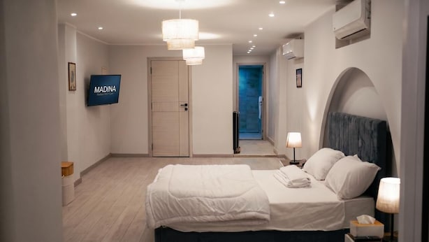 Une chambre d’hôtel avec un lit, une télévision, une porte et un couloir menant à un balcon.