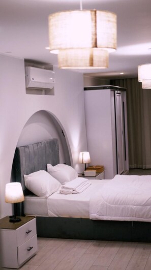 A modern hotel room with a bed, bedside tables, a lamp, a wardrobe, and a ceiling light fixture. - Madina Boutique Hotel  (Luxor)