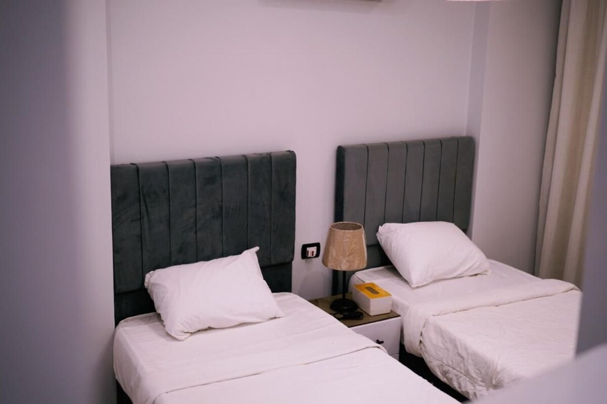 A hotel room with two beds, each with a headboard and white bedding.