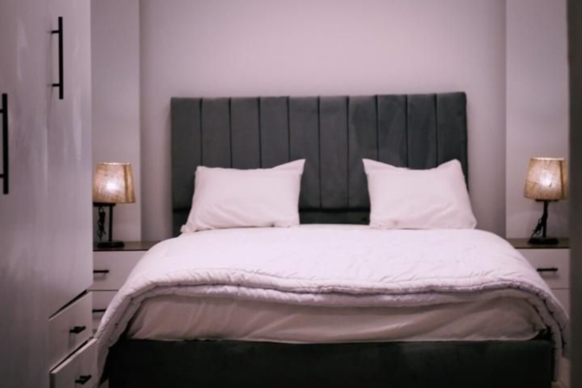 A modern bedroom with a large bed, two bedside lamps, and a ceiling light fixture.
