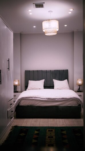 A modern bedroom with a large bed, two bedside lamps, and a ceiling light fixture. - Madina Boutique Hotel  (Luxor)