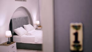 Une chambre à coucher comprenant un lit, une table de chevet, une lampe et un luminaire fixé au mur.