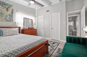 Ein Schlafzimmer mit Bett, Kommode, Schrank und einem grünen Stuhl.