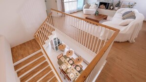 En modern inredning med en trätrappa, en matplats med ett bord för fyra personer och en vit soffa i bakgrunden.