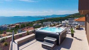 Une terrasse sur le toit dotĂ©e dâun jacuzzi, de coins salon extĂ©rieurs et offrant une vue sur la mer et les montagnes.
