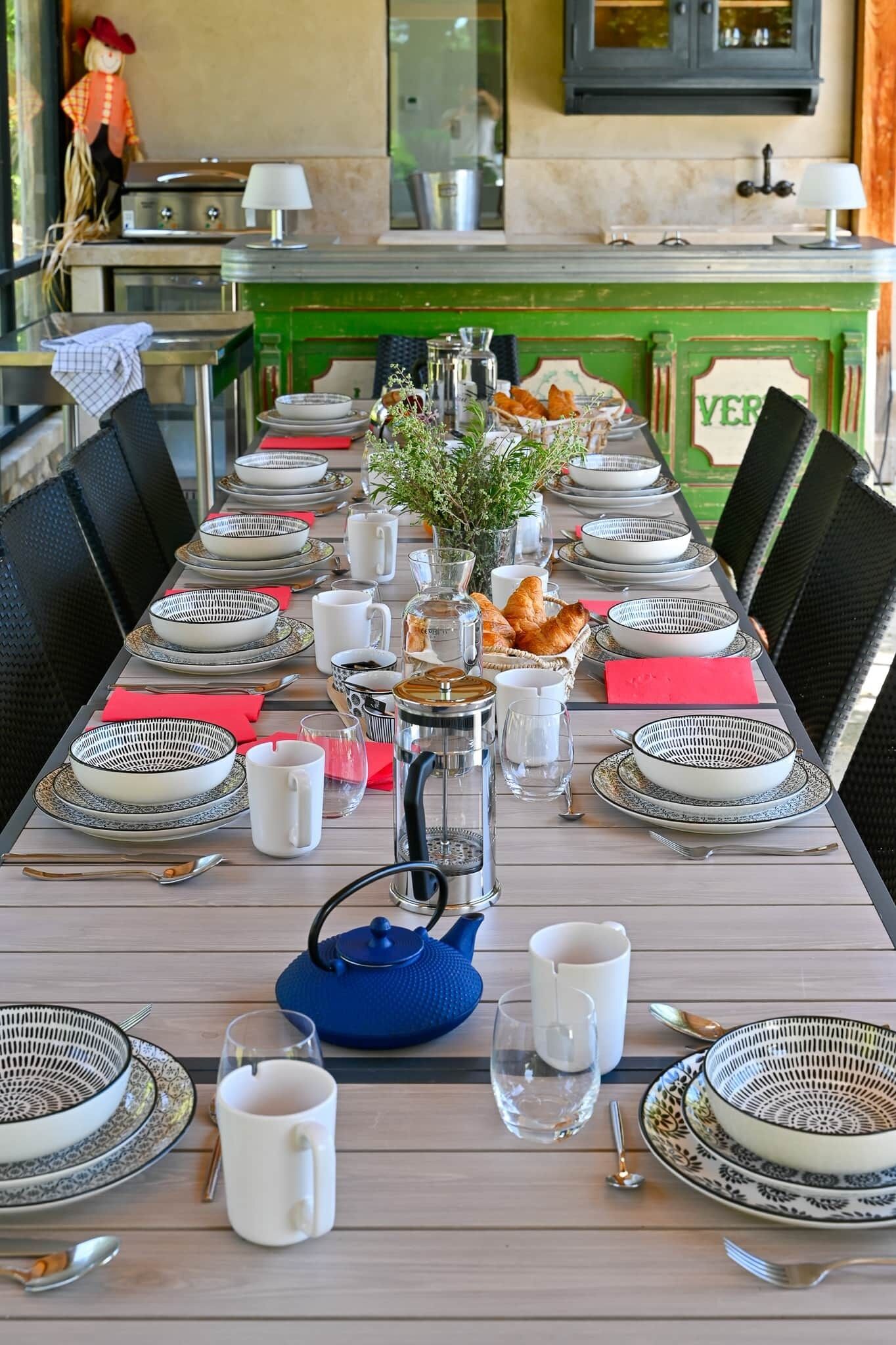 Uma mesa de jantar posta para uma refeição, com pratos, xícaras e um bule.