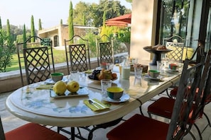 An outdoor dining area with a round table, chairs, and a variety of fruits and beverages. - Le Domaine de Laudun · 8 bedrooms · private pool (Tarascon)