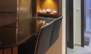Eine Küche mit dunkler Arbeitsplatte, einem Stuhl und einem Schrank mit Geschirr.