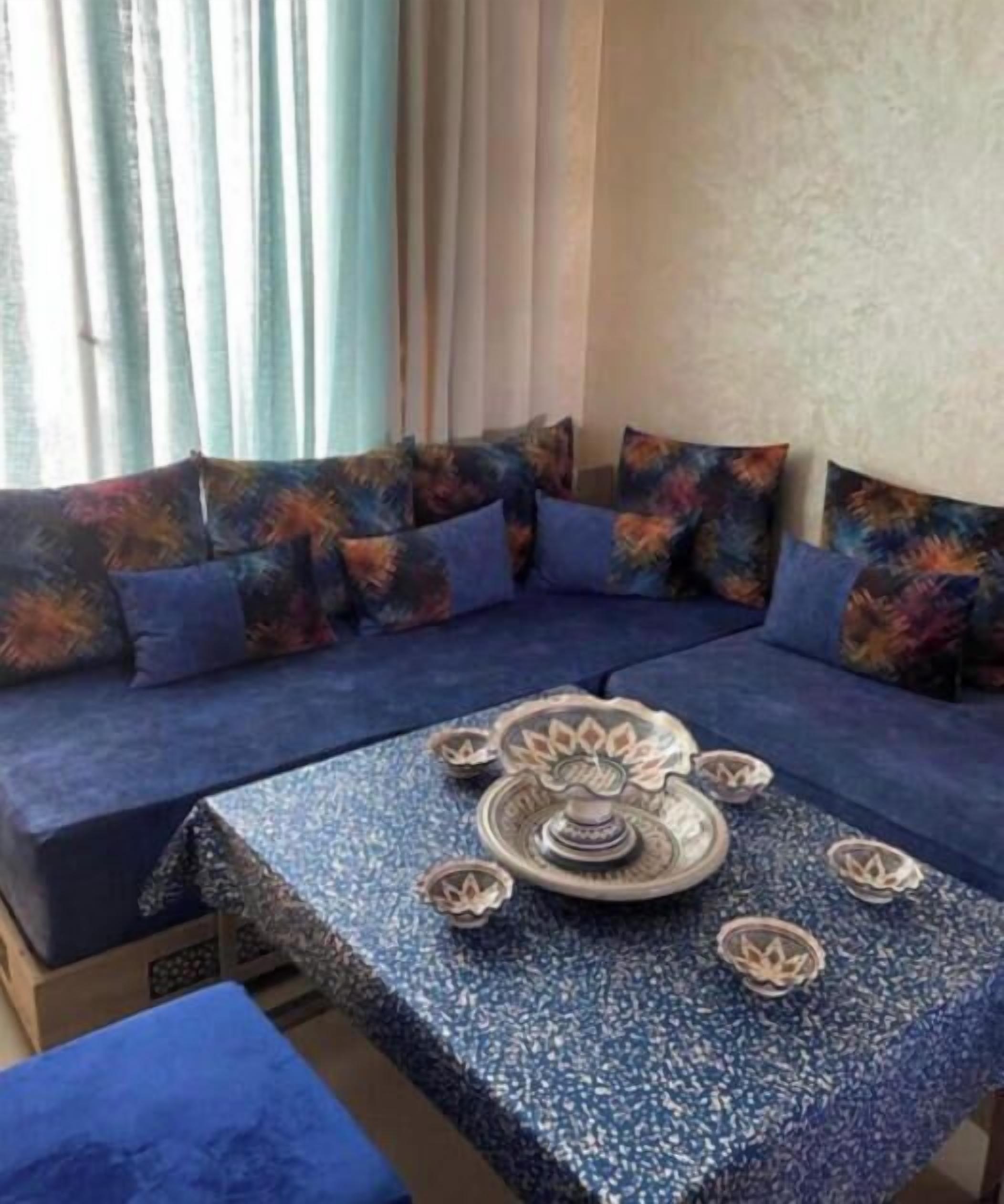 A room with a sofa set, a table with decorative items, and a window with curtains.