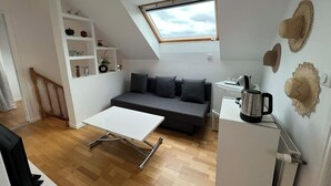 Un espacio habitable compacto con un entrepiso para dormir, un sofá, una mesa de centro y una kitchenette.